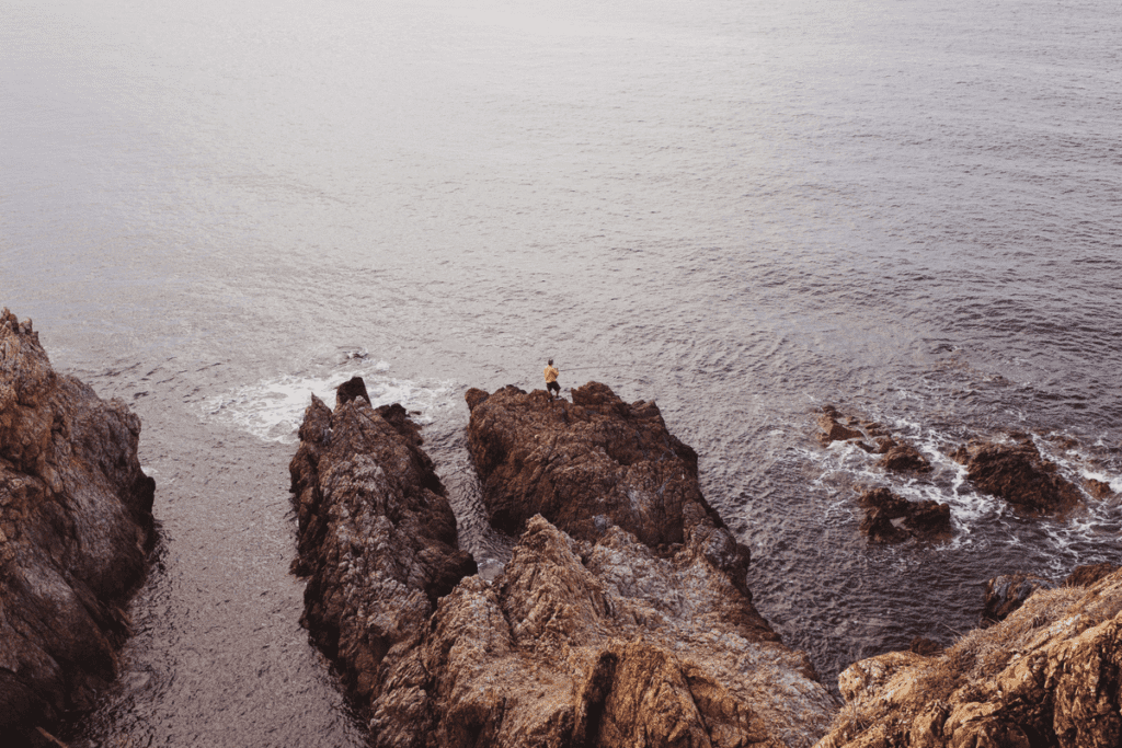 guy fishing in ocean on rocks