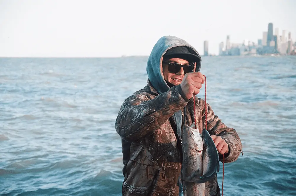 guy in hoodie and sunglasses catching fish
