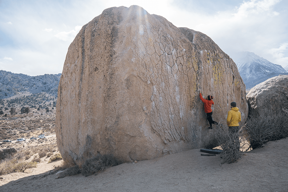 two people practicing rock climbing on boulder