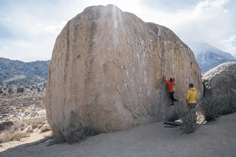 two people practicing rock climbing on boulder